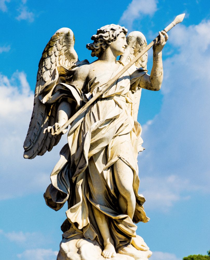 A statue of an angel. It's outside against a bright blue sky.