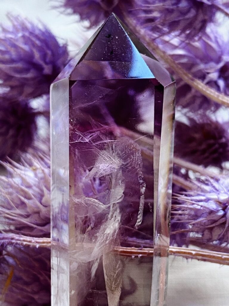 Clear crystal point with purple feathers around it.