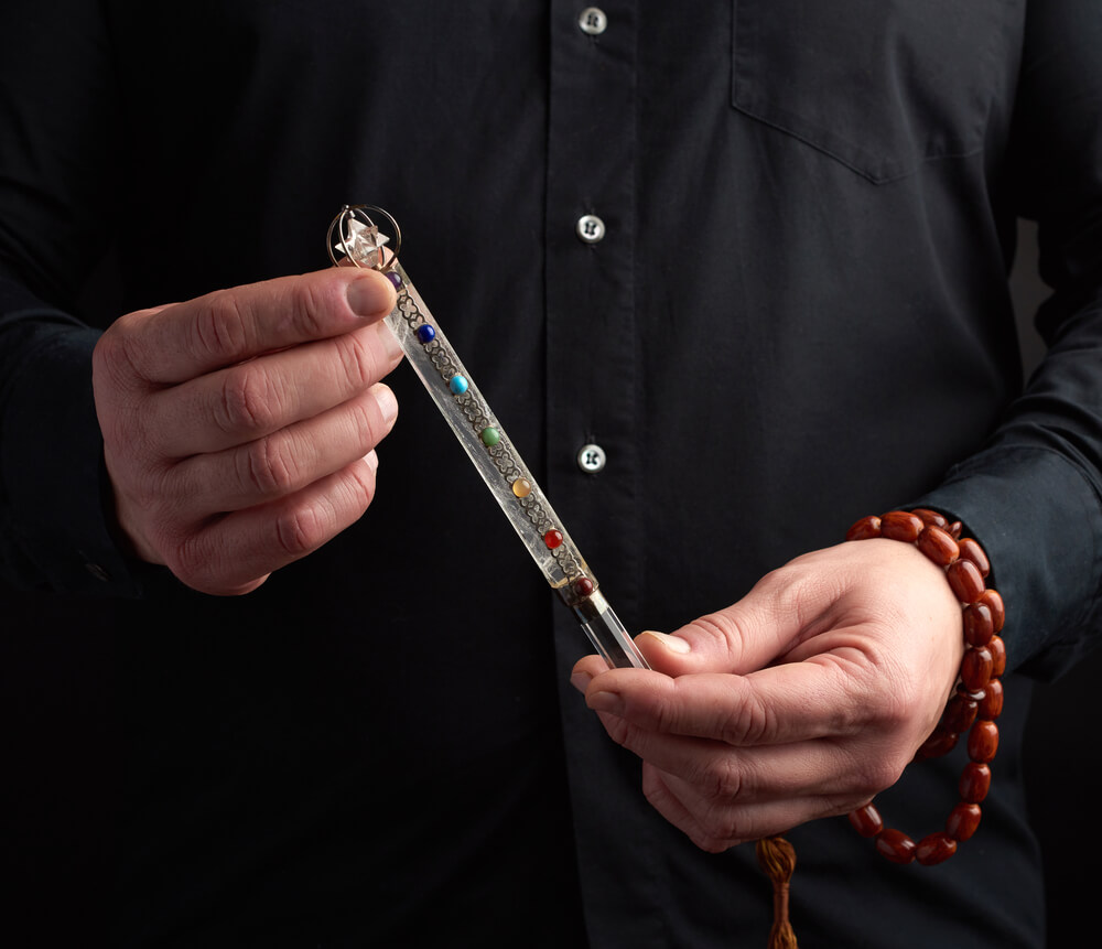 Person holding a crystal chakra wand