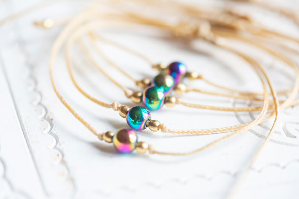 Several gold bracelets with a rainbow stone in the middle of each bracelet.