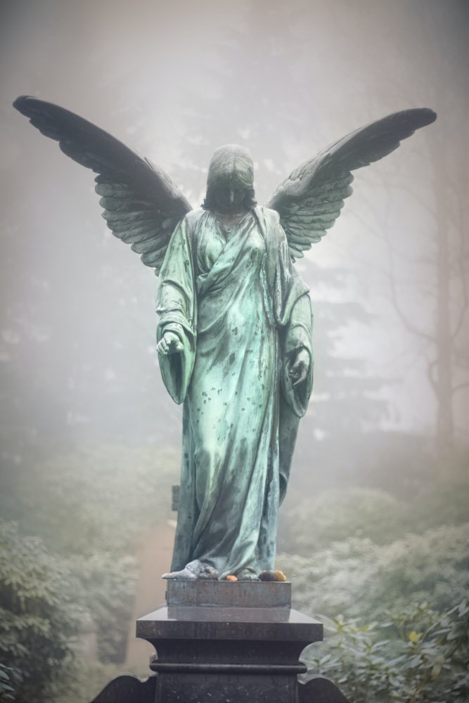 A statue of a green angel standing tall with wings.